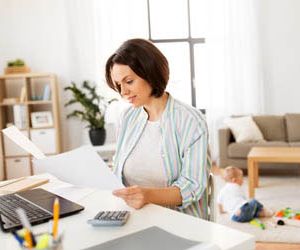 mother working with papers and baby boy at home