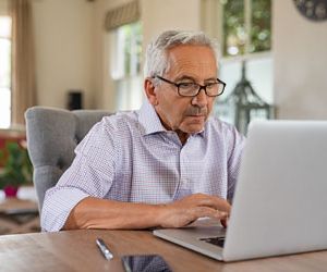 Senior man working with laptop at home. Old man using computer a