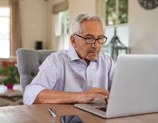 Senior man working with laptop at home. Old man using computer a