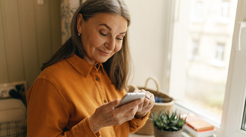 Cheerful European retired woman enjoying modern electronic gadge