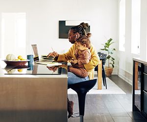 Young mom sitting with her daughter while working from home