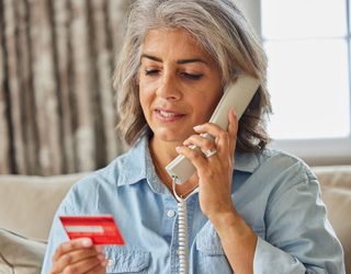 Mature Woman At Home Giving Credit Card Details On The Phone