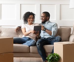 Smiling black couple use digital tablet on moving day